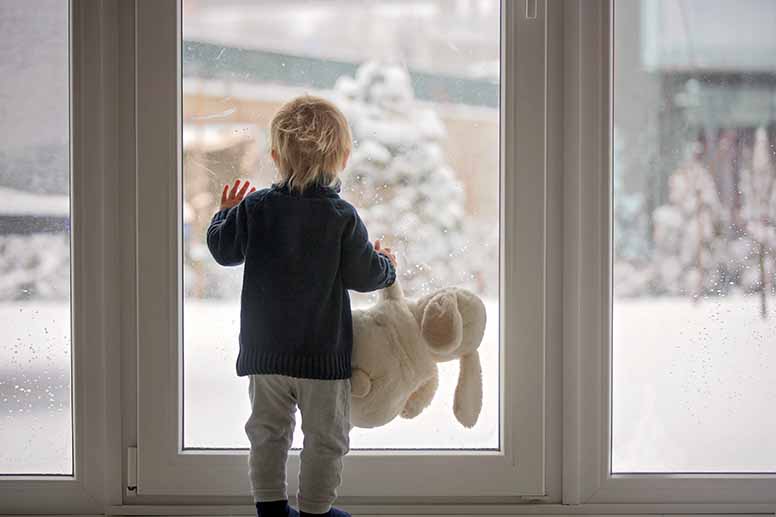 Lapsi katsoo ikkunnasta lumisadetta