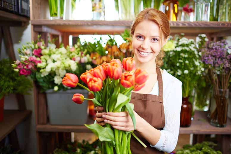 Nainen myy kukkakaupassa tulppaaneja