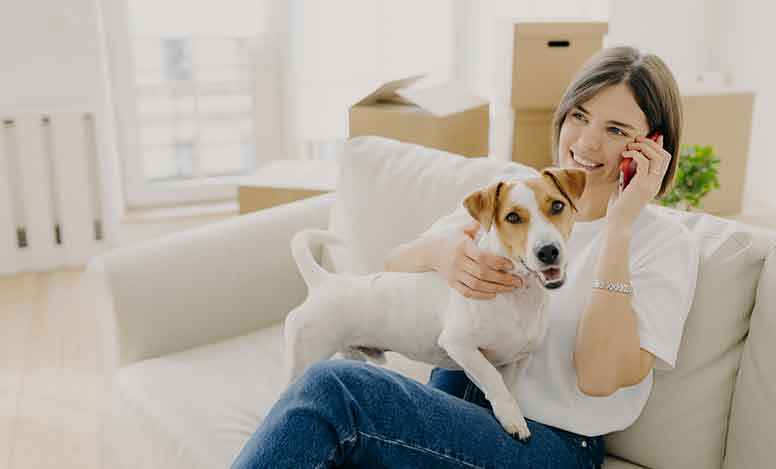 Nainen ja koira istuvat sohvalla