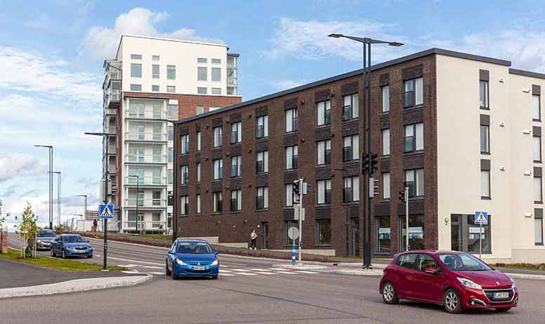 Sinisiä ja punaisia autoja uusia kerrostaloja