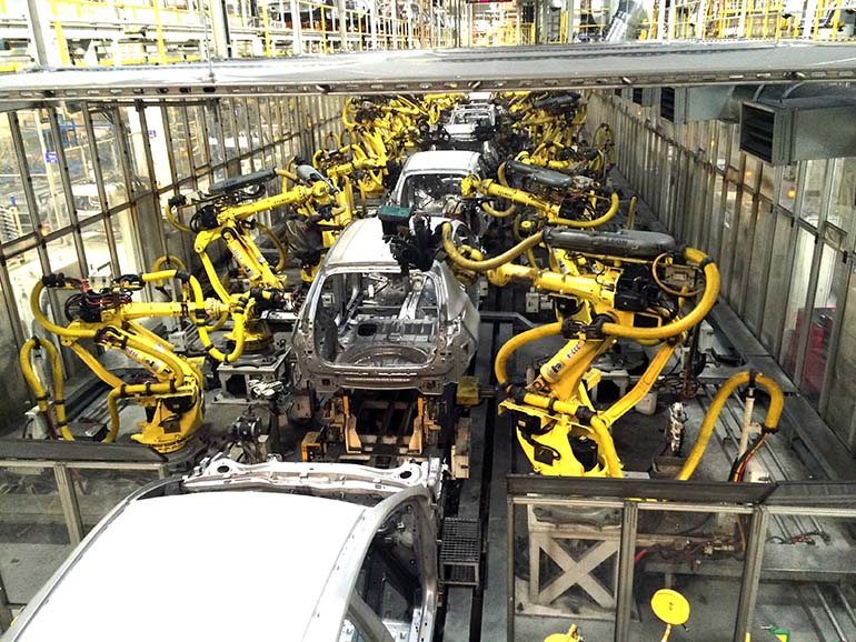 Kian modernilla tehtaalla robotit tekevät työtään ennen kuin autot päätyvät ihmisten käsiin. 