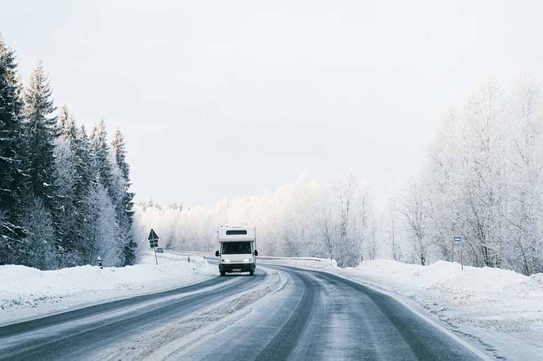 Matkailuauto ajaa lumisella tiellä