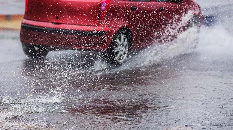 Auto ajaa lätäkköön kaatosateessa