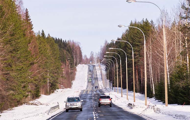 Autoja ajelee talvisella tiellä, aurinko paistaa