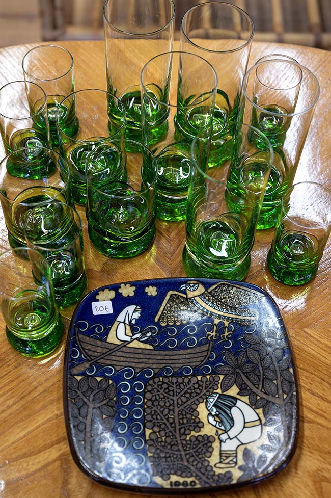 Pöydällä on vihreät Humppilan Kievari-juomalasit sekä Kalevala-lautanen. Kuva: Leena Louhivaara