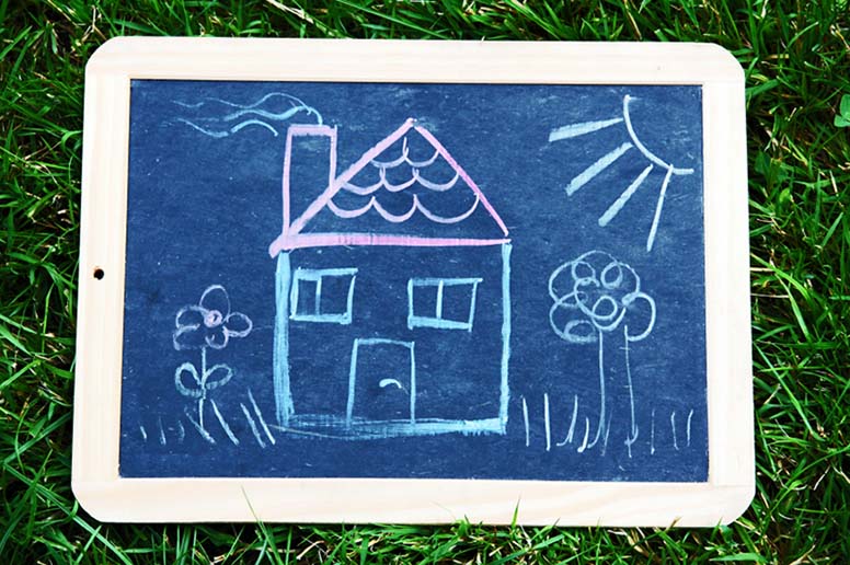 Liitutauluun piirretty omakotitalo ja kukkia