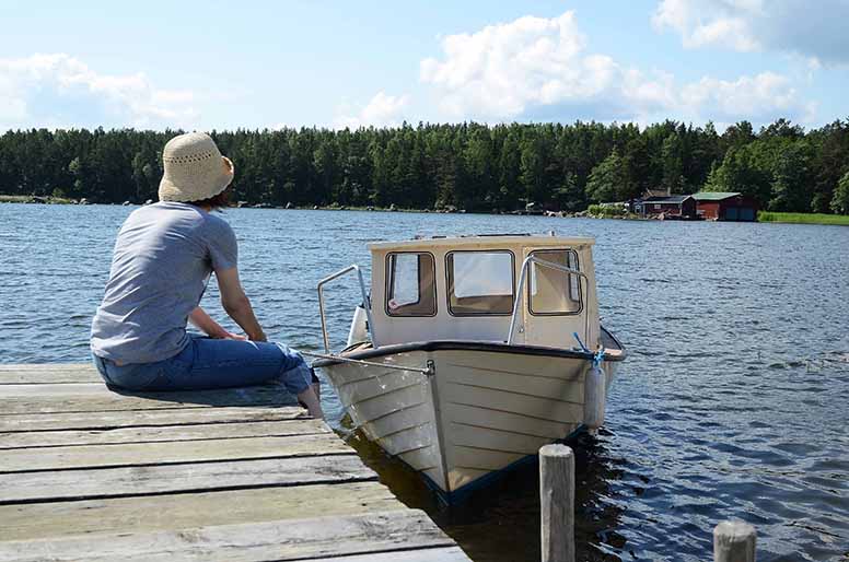 Nainen istuu laiturilla ja pitelee venettä