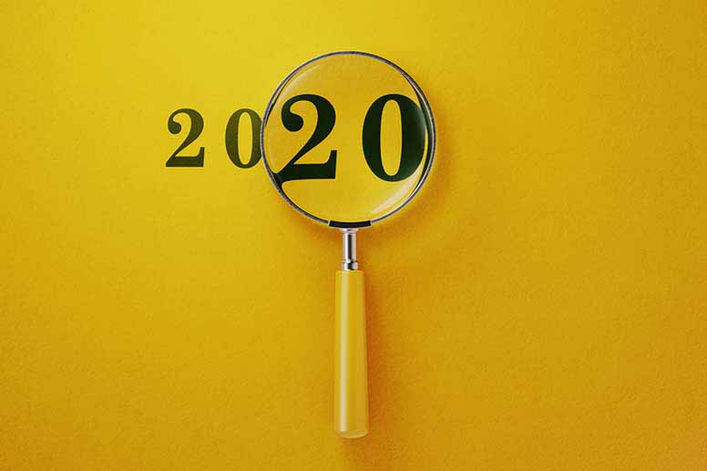 Vuosi 2020 ja suurennuslasi keltaisella pöydällä