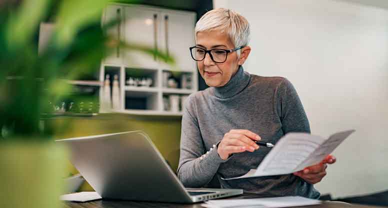 Harmaatukkainen nainen työskentelee toimistossa