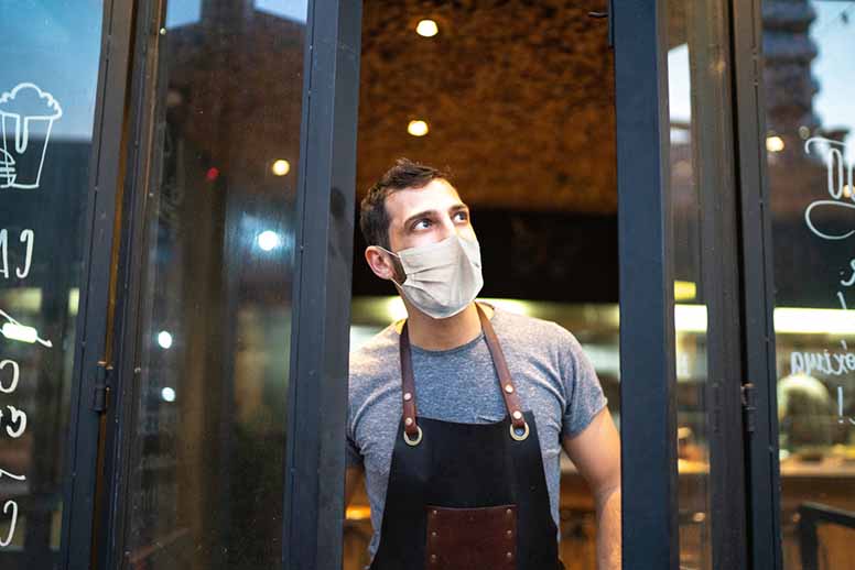 Huolestunut yrittäjä kahvilansa ovella