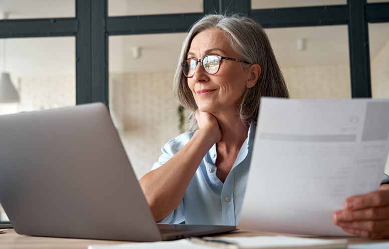 Tietokone, nainen, silmälasit, papereita