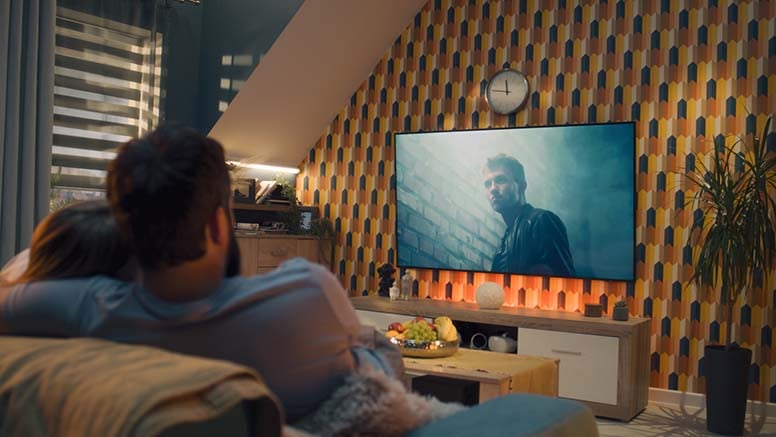Pariskunta istuu sohvalla ja katselee televisiota