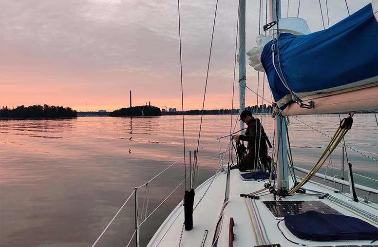 Purjevene merellä, aurinko laskee