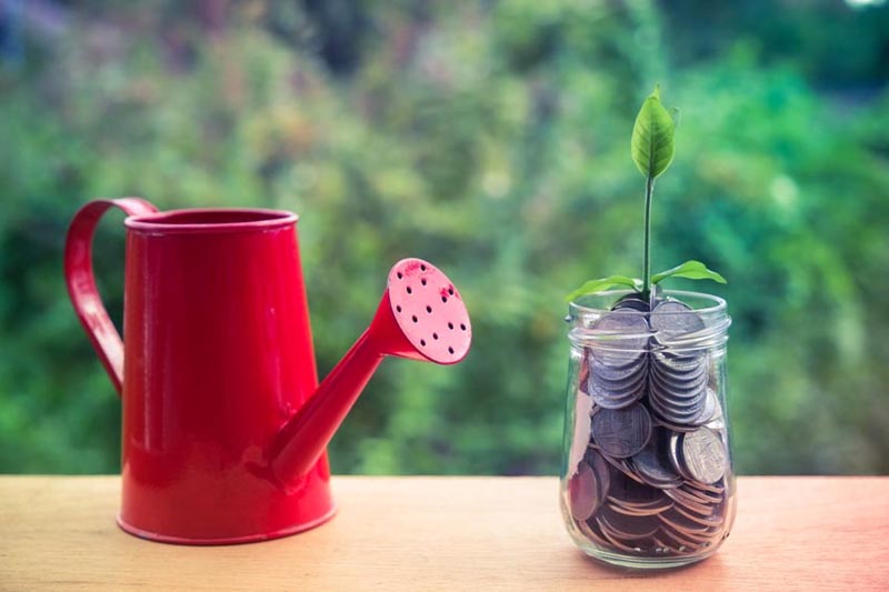 Punainen kastelukannu ja rahapurkki