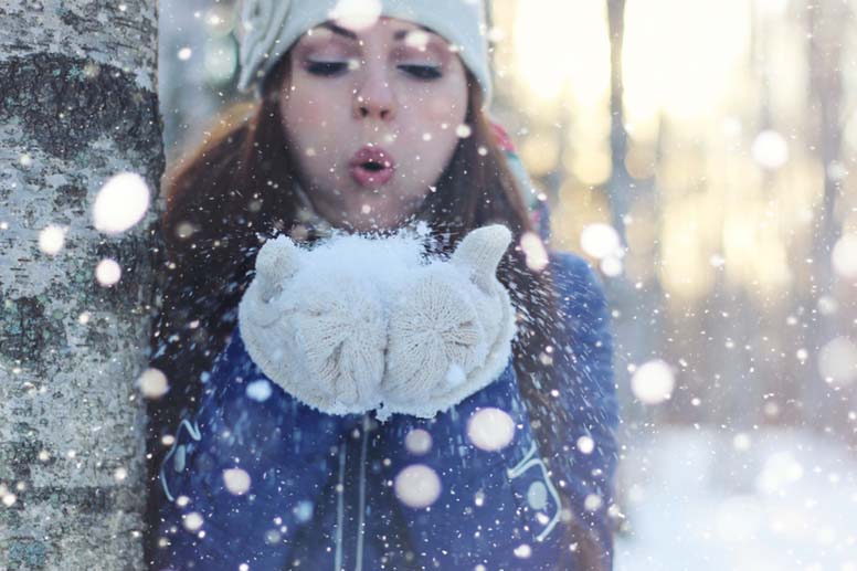 Tyttö puhaltelee lumihiutaleita