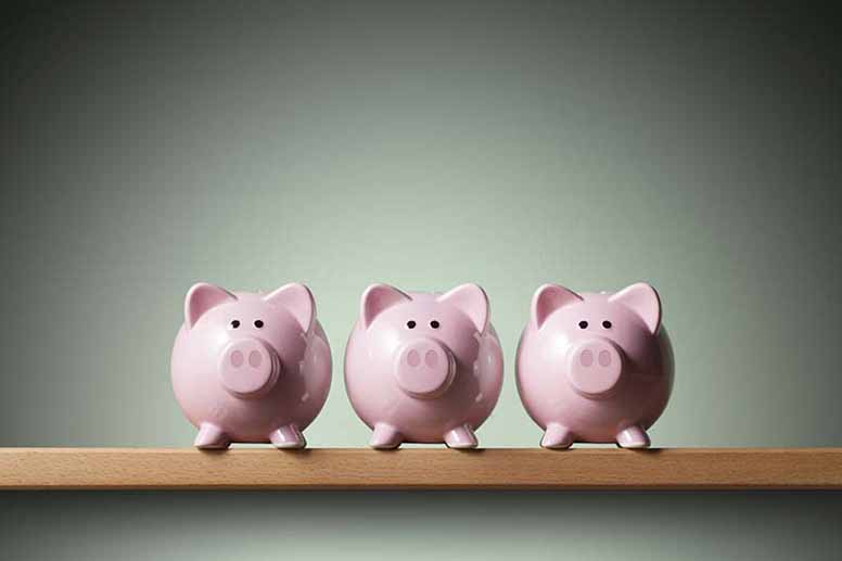 Kolme säästöpossua seisoo rinnakkain hyllyssä