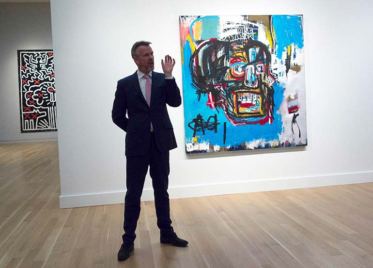 Sothebyn taidehuutokaupan työntekijä esittelee Basquiatin Untitled 1982 -maalausta. Kuva:Lehtikuva