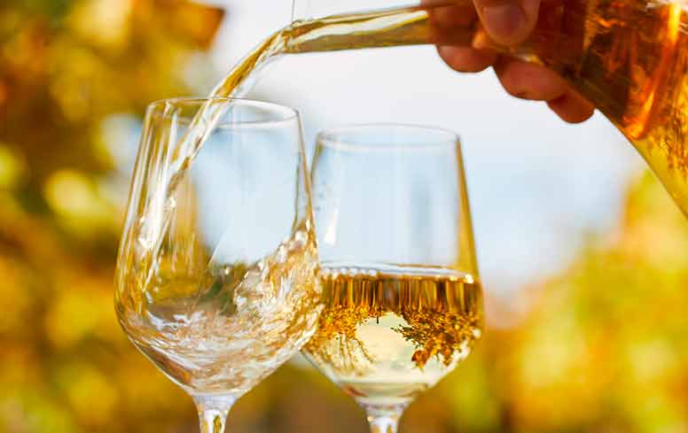 Viinilasiin kaadetaan valkoviiniä